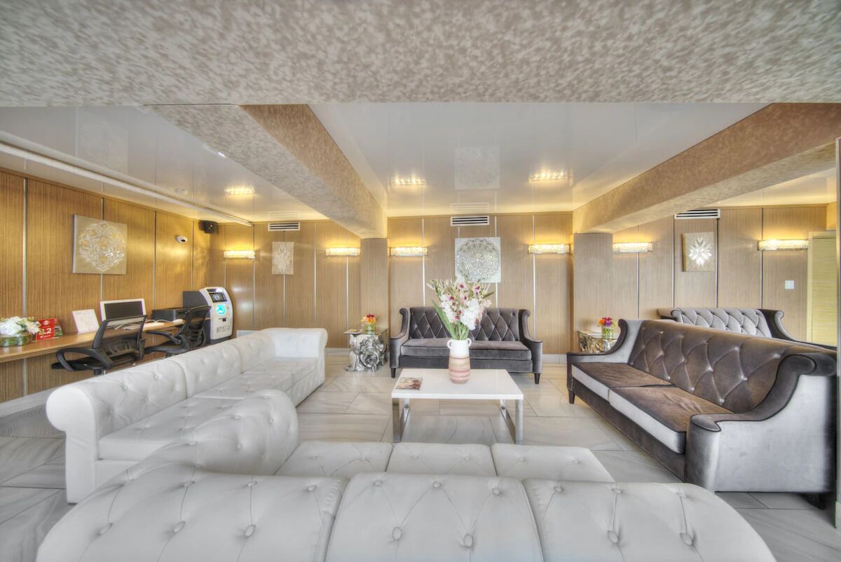 A modern hotel lobby with a seating area, a reception desk, and artwork on the walls.