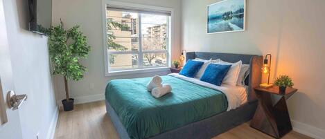 Une chambre à coucher avec un lit, une fenêtre, une plante et un tableau.