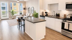 Une cuisine moderne dotée d’un îlot central, d’appareils électroménagers en acier inoxydable et donnant sur un balcon.