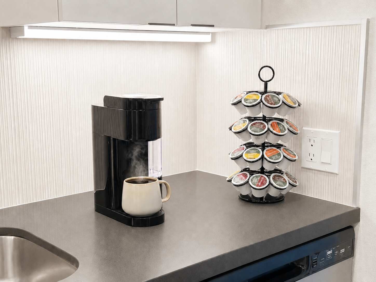 A coffee maker with a mug on a countertop, a coffee pod holder, and a dishwasher.