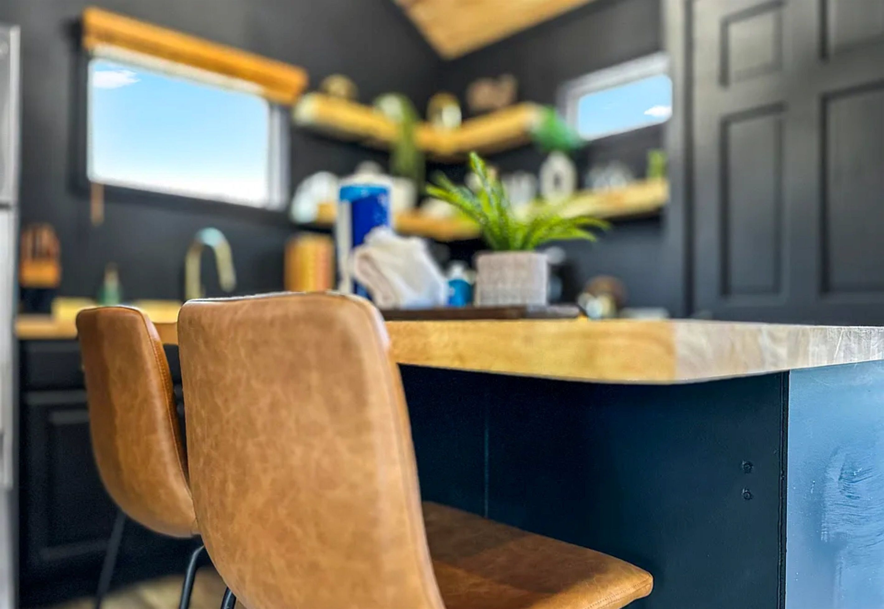 A kitchen with a wooden chair, a countertop, and a potted plant.