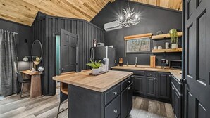 A modern kitchen with dark cabinetry, a wooden ceiling, and a central island. - Honeymoon Hideaway • Hot Tub • Fire Pit (Sevierville)