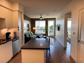 A modern kitchen with a dining area, a ceiling fan, and a view to the outside. - Stylish Apartment Near Disneyland w/ Pool & Gym (Santa Ana)