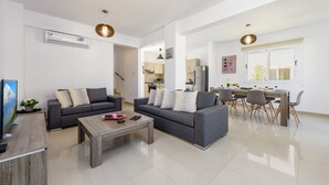 A modern living room with a sofa, coffee table, and dining area. - Nissini Villa 8 in Ayia Napa (Ayia Napa)