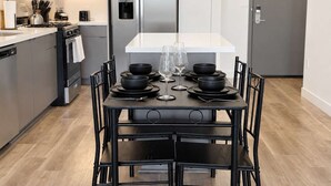 Ett modernt kök med ett matbord för fyra personer, utrustat med svarta skålar och vinglas.