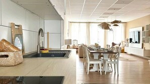 Een moderne keuken met een centraal eiland, witte kastjes en een eethoek met een tafel en stoelen.