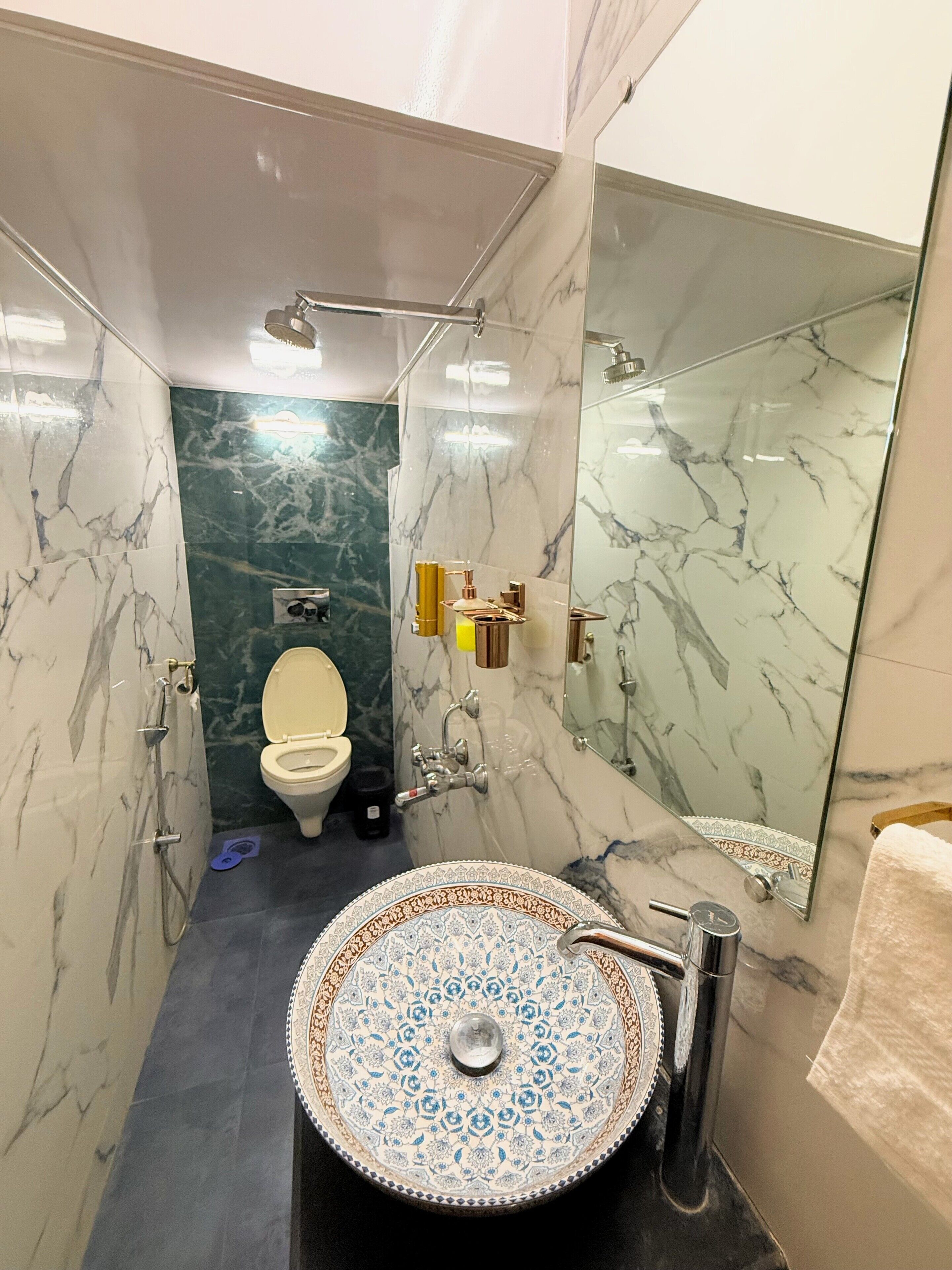 A bathroom with a marble vanity, a large mirror, and a shower area.