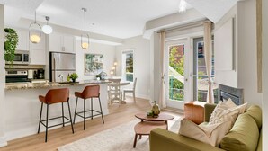 A modern kitchen with a central island, bar stools, and a dining area with a table and chairs. - 13th Ave - DT Calgary - 2BD 2BA - Sleeps 5 (Calgary)