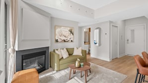 A modern living room with a fireplace, a green sofa, a coffee table, and a large floral painting on the wall. - 13th Ave - DT Calgary - 2BD 2BA - Sleeps 5 (Calgary)