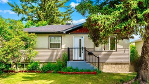A single-story house with a front porch, a small staircase, and a well-maintained lawn. - The Owlet Nwcalgary Queenbd Privatesuite (Calgary)
