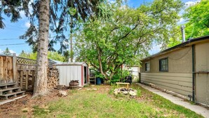 A residential backyard with a wooden deck, a shed, a tree, and a house. - The Owlet Nwcalgary Queenbd Privatesuite (Calgary)