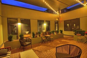Une terrasse extérieure avec des sièges, des plantes et un plafond illuminé de lumière bleue.