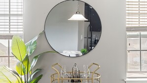 A room with a round mirror, a gold-framed table with glasses and a silver pitcher, and a large green plant. - Upscale King 3BR Townhouse in Pineville (Pineville)