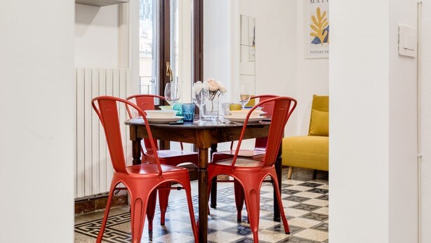 Un comedor con una mesa de madera, sillas rojas y un sofá amarillo.