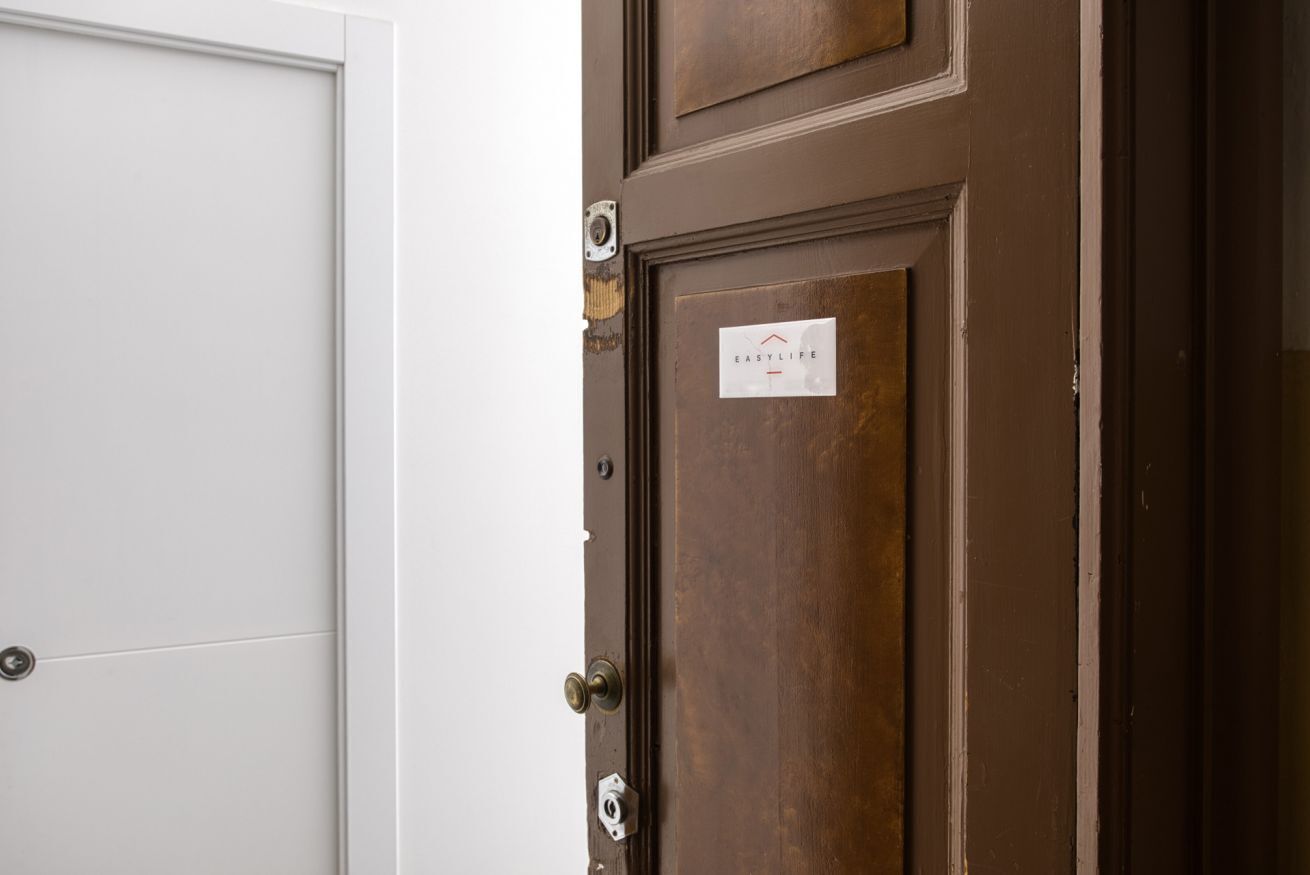 A brown door with a sign that reads "EASY LIFE" and a white door next to it.