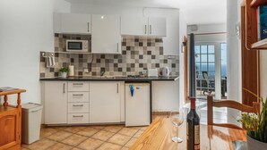A compact kitchen with white cabinets, a microwave, a toaster, and a sink.
