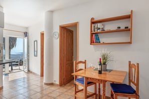 Un comedor con una mesa de madera, sillas, una planta en maceta y una estantería.