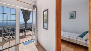 A room with a bed, a small table, and a view through a glass door.
