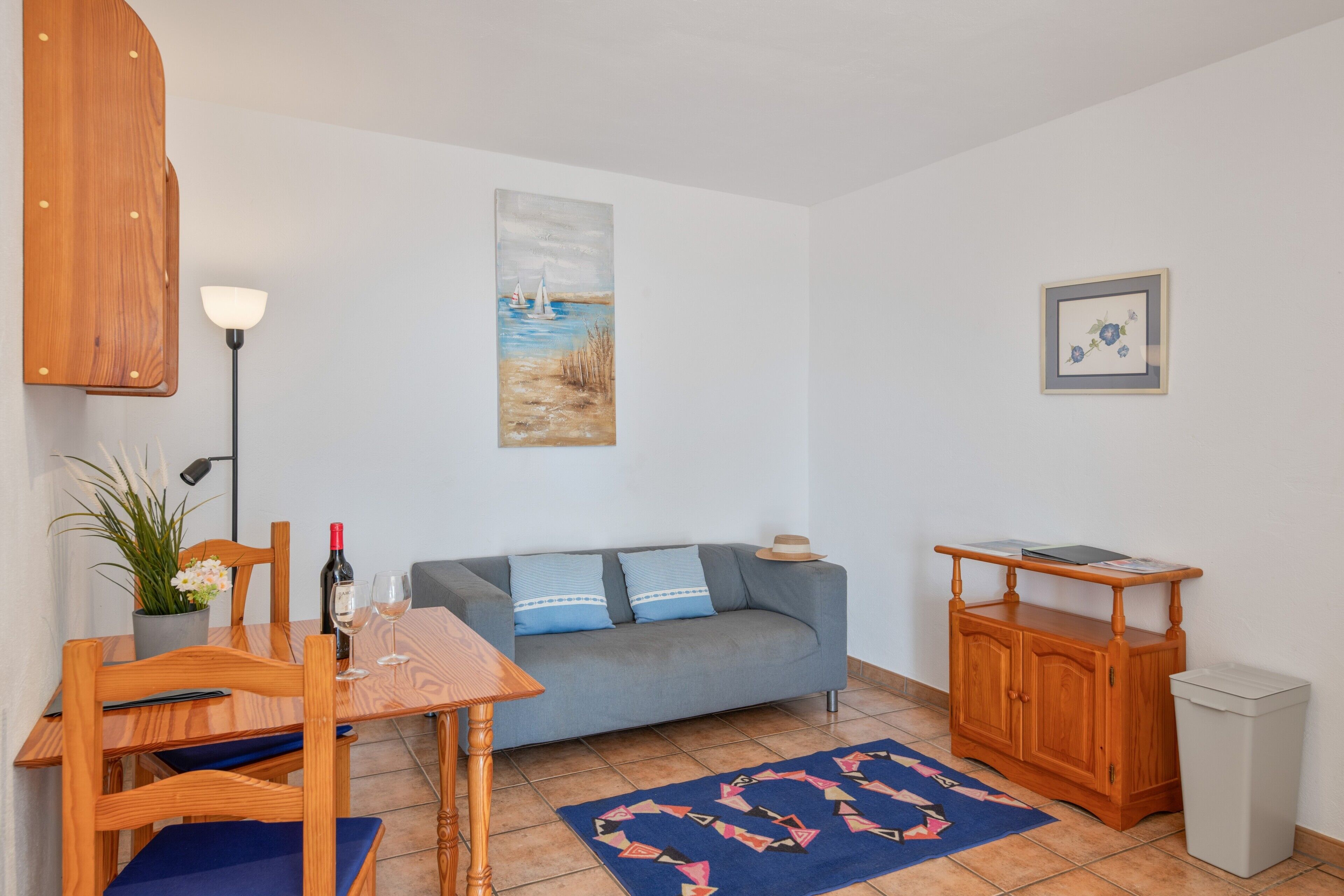 A living room with a sofa, a dining table, a lamp, a painting, and a cabinet.