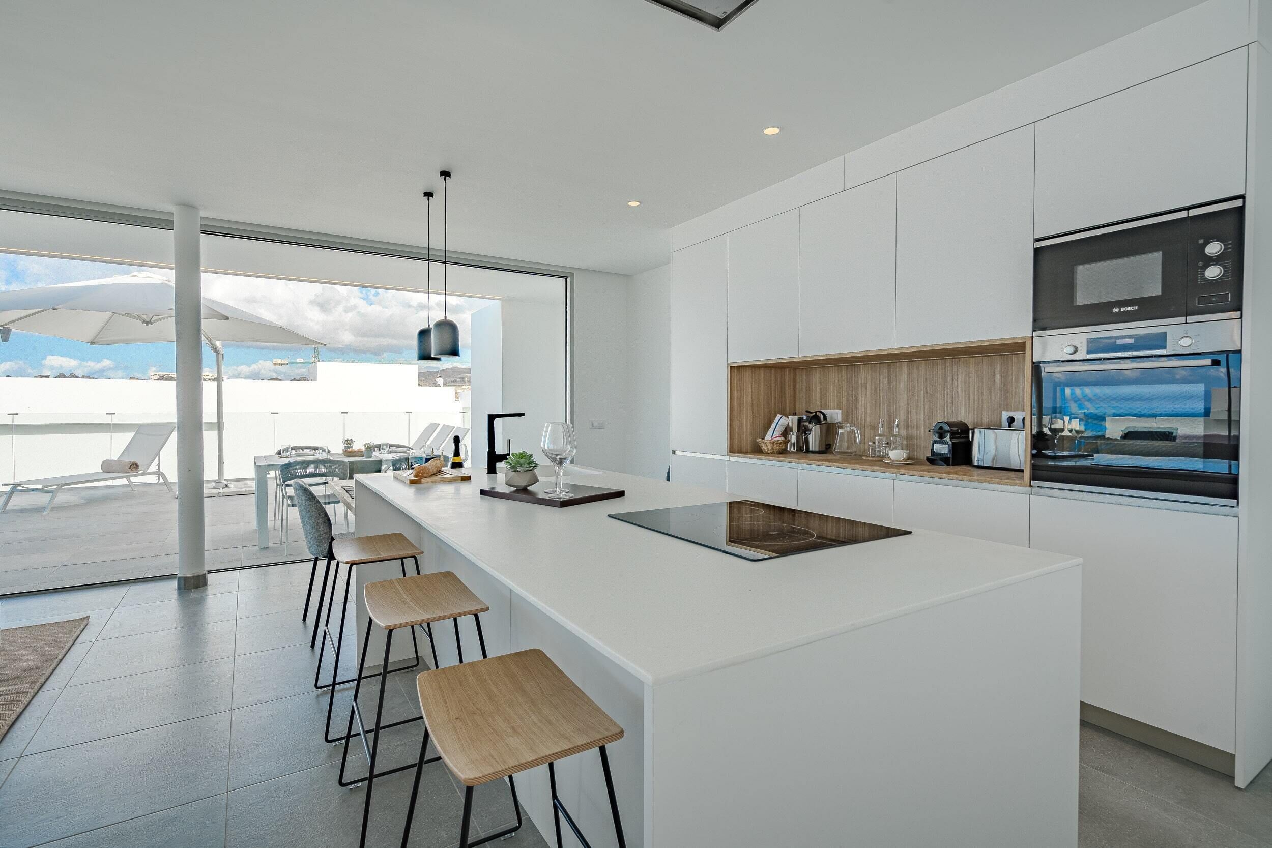 Une cuisine moderne dotée d’un grand îlot central, de tabourets de bar et d’appareils électroménagers intégrés.