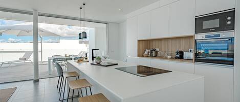Une cuisine moderne dotée d’un grand îlot central, de tabourets de bar et d’appareils électroménagers intégrés.