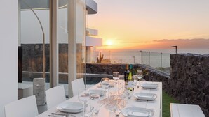 A dining table set for six with wine glasses and plates, overlooking a sunset over the ocean. - Casangular by Upper (Adeje)