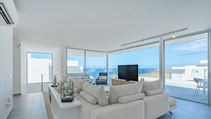 A modern living room with a sofa, TV, and a view of the sea. - Casangular by Upper (Adeje)