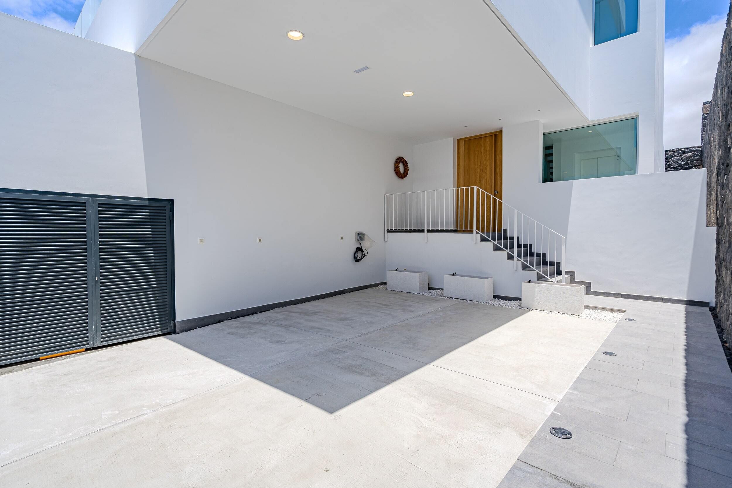 A modern building with a concrete patio, a wooden door, and a staircase with white railings.