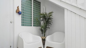 A white door with a 'WELCOME' mat, a potted plant, and two white plastic chairs. - Ocean Park Studio | Near Beach | Smart TV + Wi-Fi (San Juan)