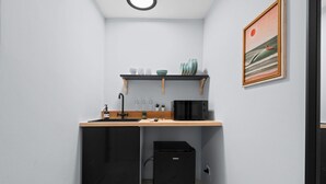 A compact kitchen with a sink, a microwave, a small refrigerator, and a shelf with dishes and cups. - Ocean Park Studio | Near Beach | Smart TV + Wi-Fi (San Juan)