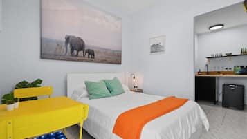 Un dormitorio con cama, escritorio, silla y un refrigerador pequeño.