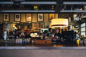 Zona de bar con mostrador, varias botellas y una lámpara colgante.