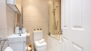 A modern bathroom with a glass-enclosed shower, a white toilet, and a bathtub. - Chic 1BR Close to Buckingham Palace (London)