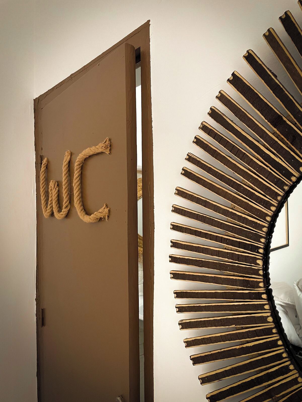 Una habitación con una puerta que indica “WC” y una decoración de pared con un diseño de sol original.