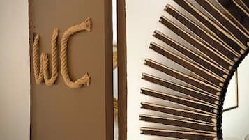 Une pièce avec une porte portant l’inscription « WC » et une décoration murale originale en forme de soleil rayonnant.