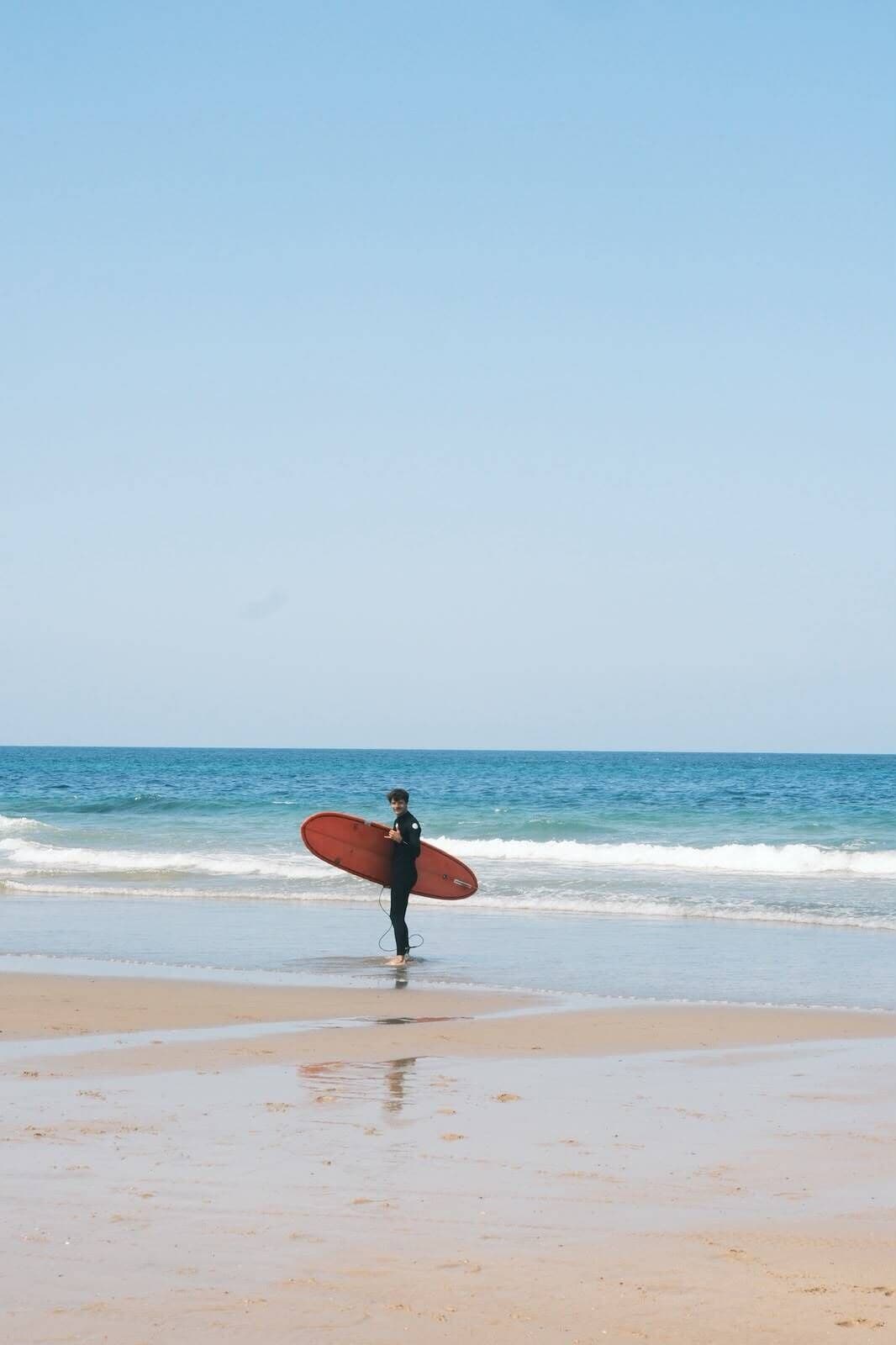 A person holding a surfboard on a beach.