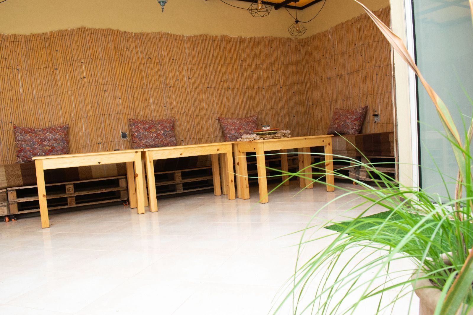 A room with a bamboo wall, a wooden bench, and a potted plant.