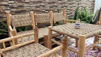 Wicker furniture with a woven seat and backrest, a woven table, and a stone-patterned wall.
