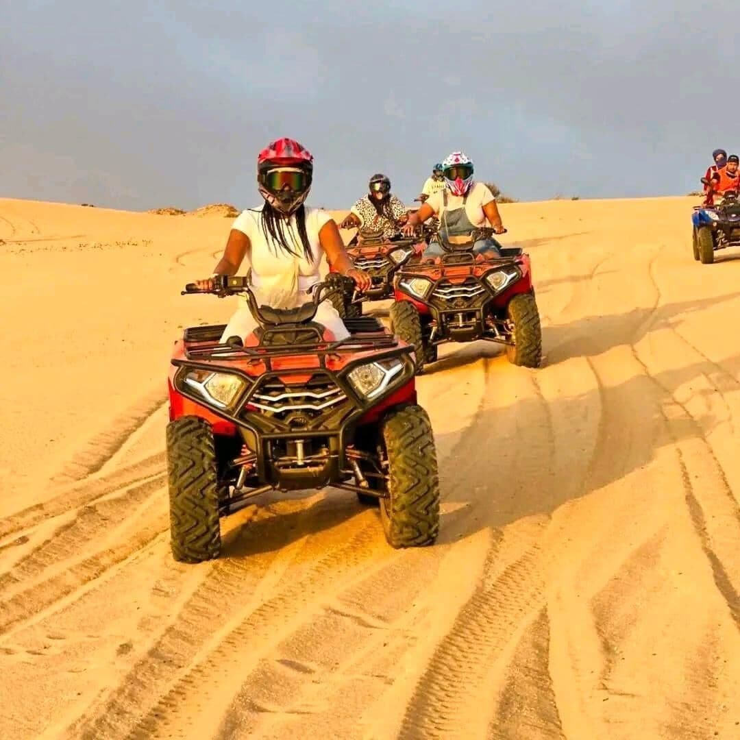 Un groupe de personnes conduisant des quads sur un terrain sablonneux.