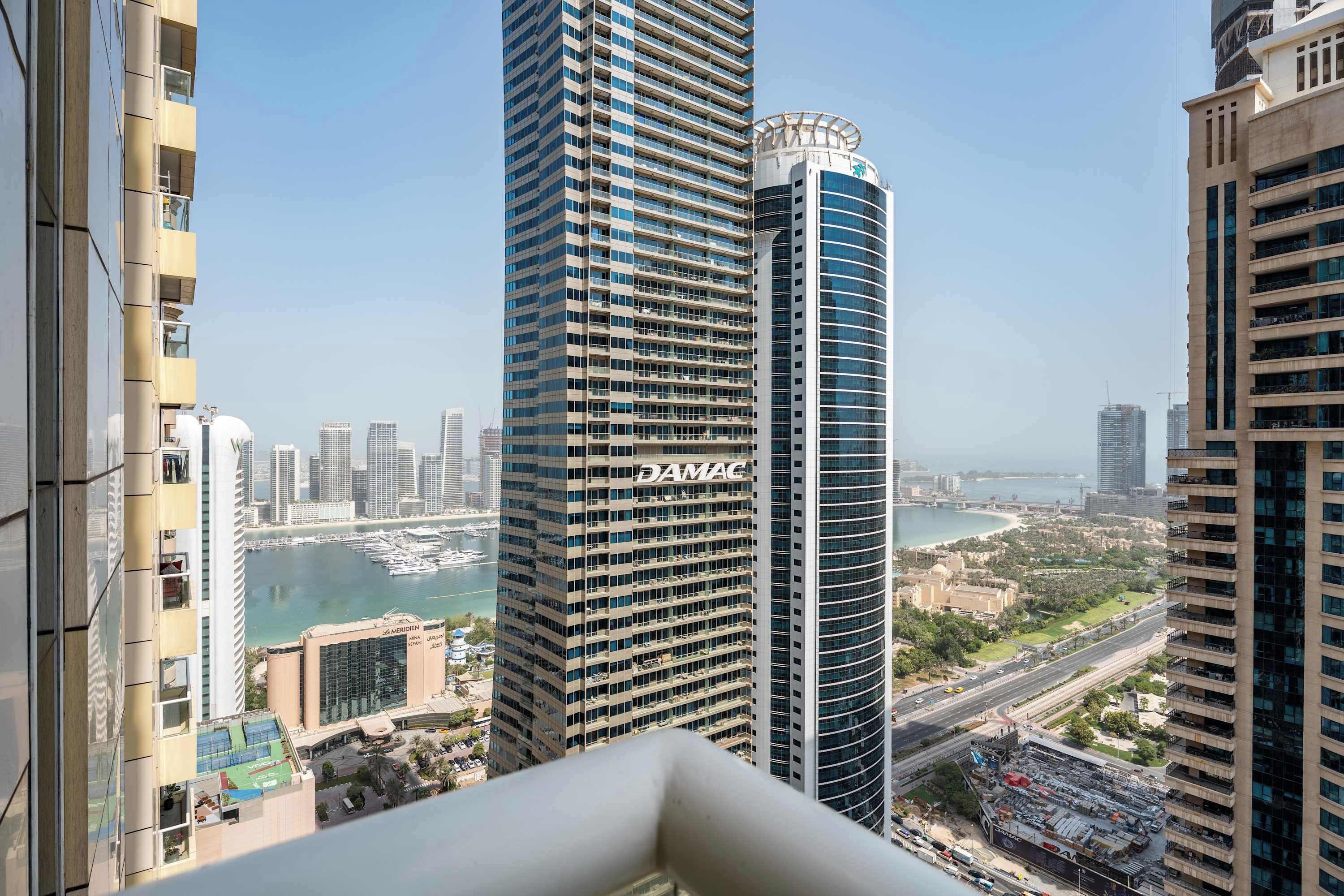 A high-rise building with a view of a marina and cityscape.