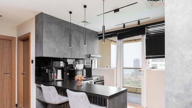 Een moderne keuken met een centraal eiland, barstoelen en een stadsgezicht door grote ramen.
