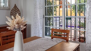A dining area with a table, chairs, a vase with dried flowers, a decorative leaf, and a view through a window with a metal grid. - Holiday Home 'El Rincón Sevillano' with Private Terrace, Wi-Fi and Air Conditioning (Gerena)