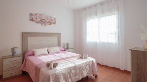 A bedroom with a bed, bedside tables, a ceiling fan, and a window with curtains. - Holiday Home 'El Rincón Sevillano' with Private Terrace, Wi-Fi and Air Conditioning (Gerena)