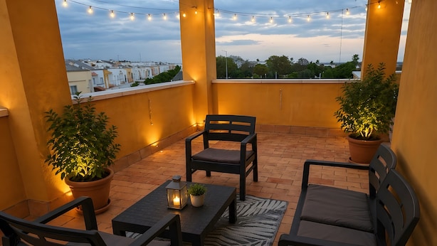 A balcony with outdoor furniture, potted plants, and string lights. - Holiday Home 'El Rincón Sevillano' with Private Terrace, Wi-Fi and Air Conditioning (Gerena)