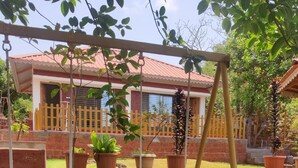 A backyard with a swing set, potted plants, and a brick wall. - The Alphonso Mango County (Anjarle)
