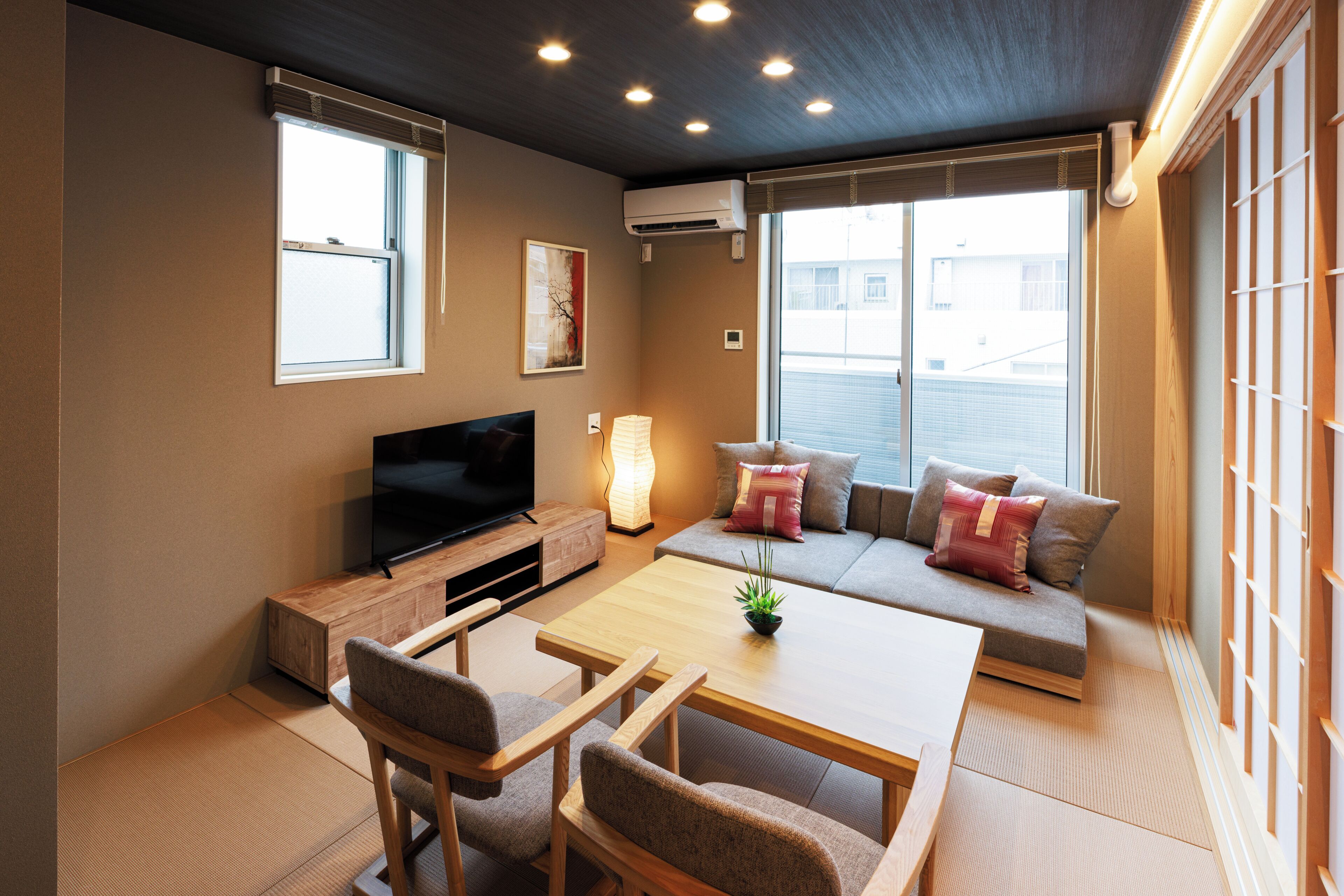 A modern living room with a flat-screen TV, a sofa with cushions, a coffee table, and a potted plant.