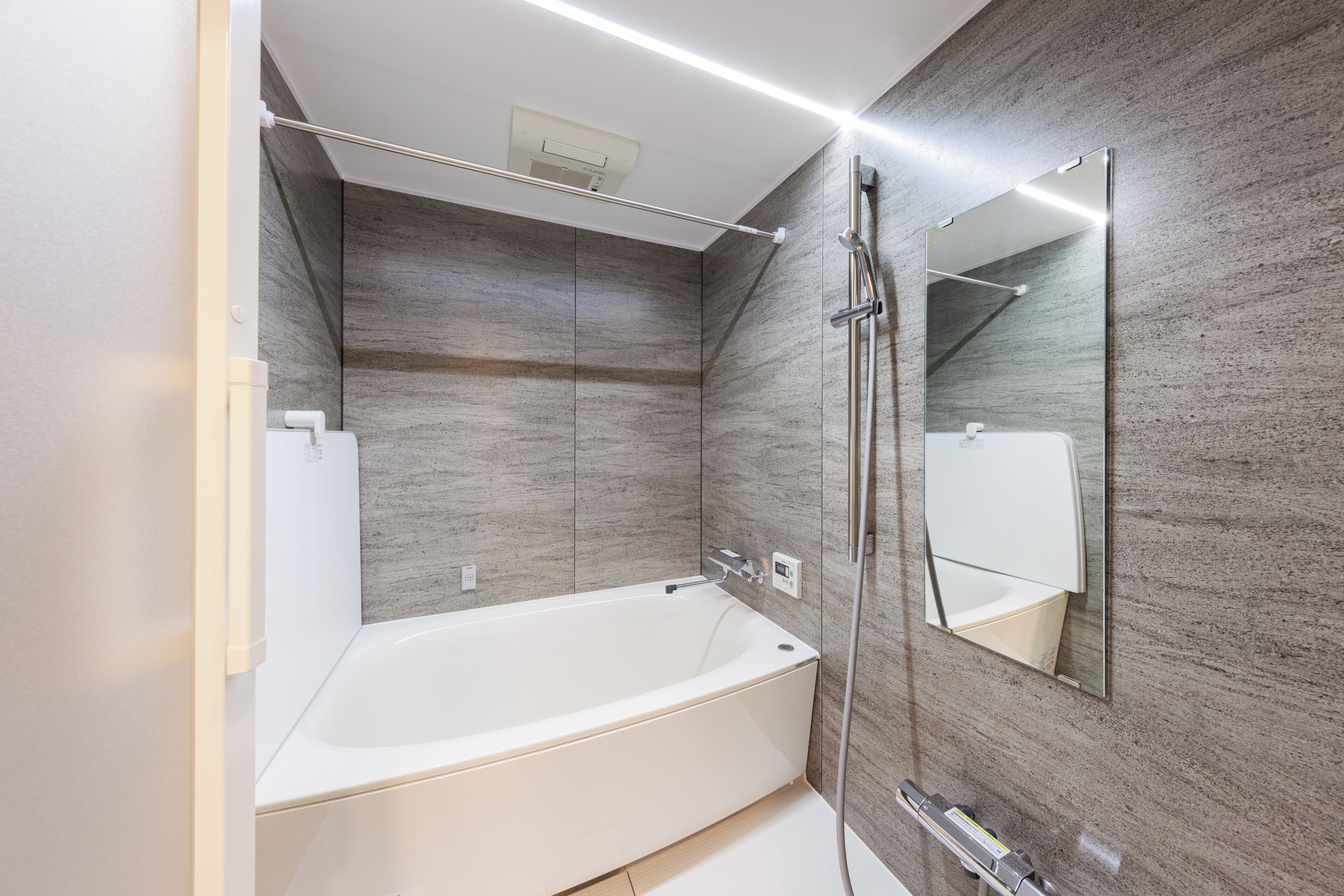 A modern bathroom with a freestanding bathtub, a wall-mounted mirror, and a showerhead.