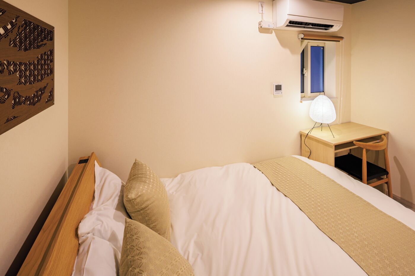 Una habitación de hotel con cama, escritorio y aire acondicionado.
