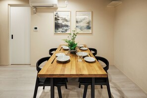A dining area with a wooden table, black chairs, a potted plant, and two framed artworks on the wall. - Cityzen Tokyo (Tokyo)