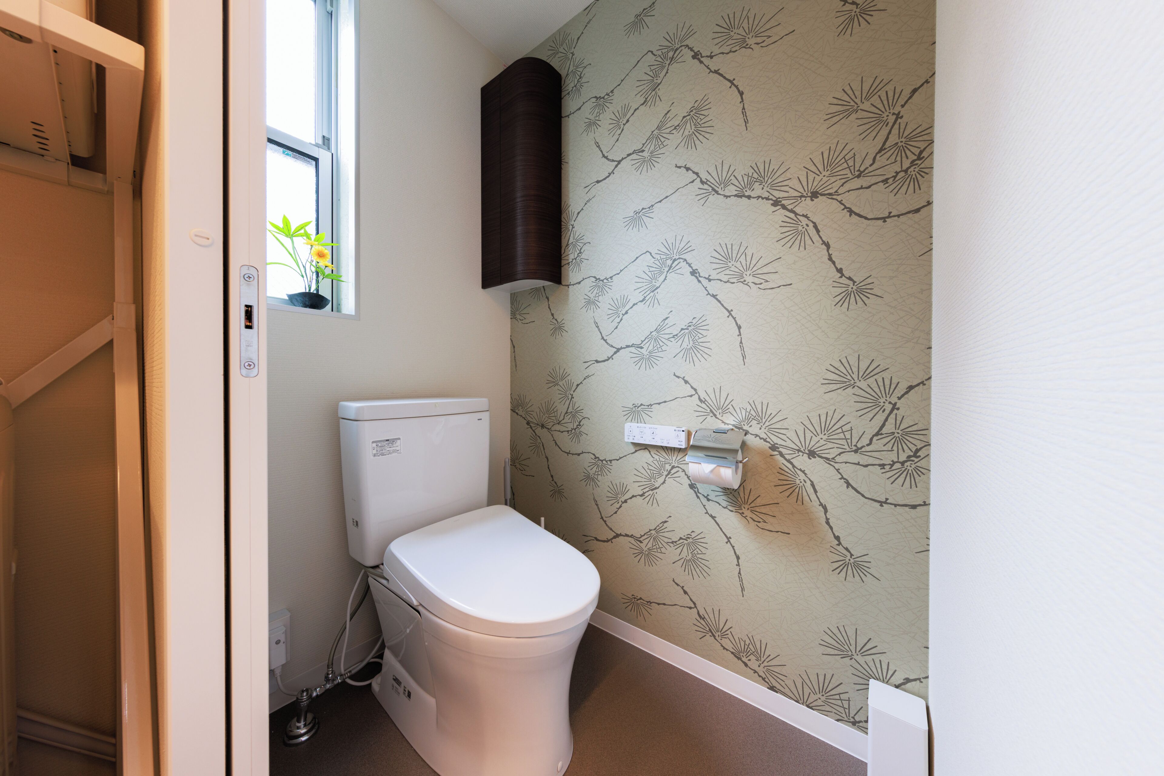 A small bathroom with a toilet, a window, and a wall-mounted towel rack.